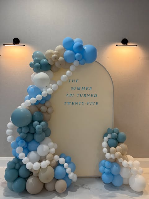 Blue, white, and cream balloon décor framing a celebration backdrop